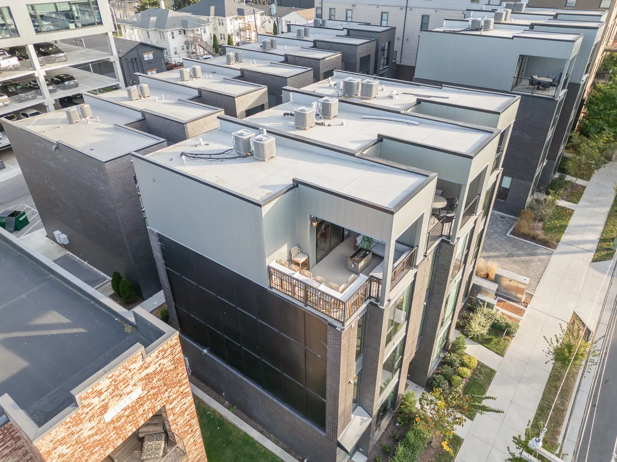 This exterior image showcases a modern building with striking architectural lines, an outdoor balcony, and tasteful landscaping. The setting suggests a sophisticated, contemporary environment perfect for both leisure and gatherings. The balcony area hints at spaces where guests might relax, network, or work remotely while taking in the urban surroundings.
